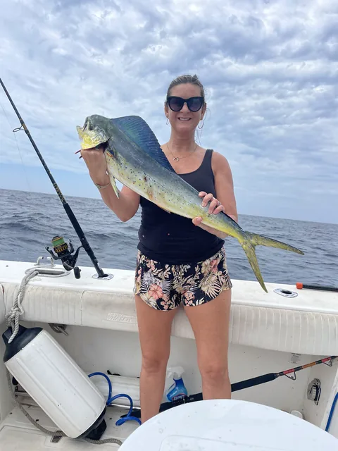 Guest holding a colorful dorado at the rail on a cloudy day.