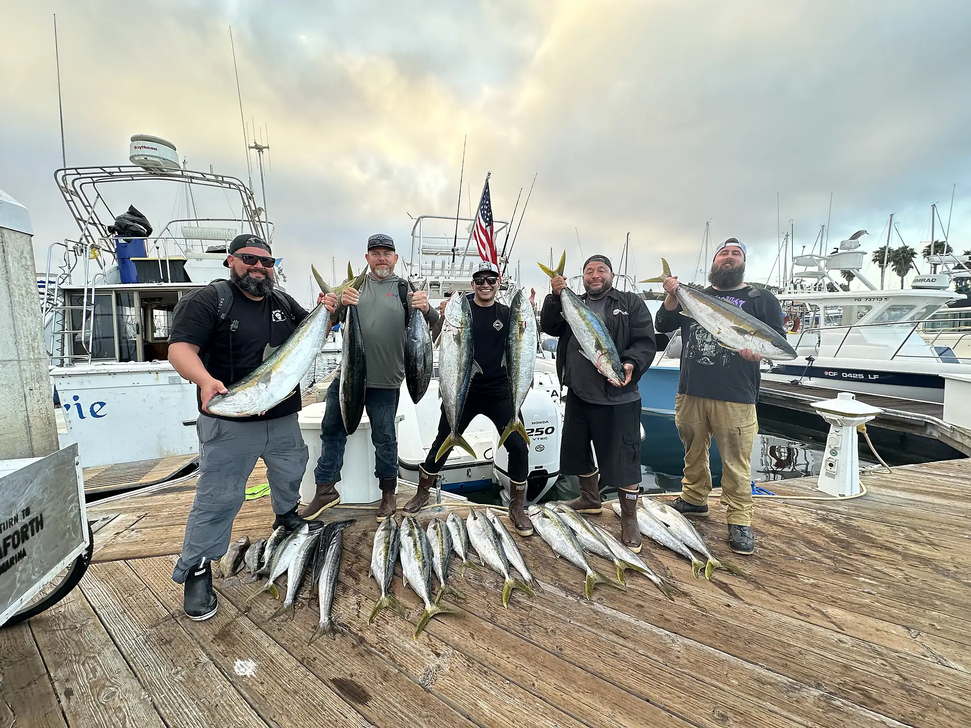 A Fernandez Charters crew on the dock in Mission Bay holding a haul of yellowtail after a six-pack charter trip