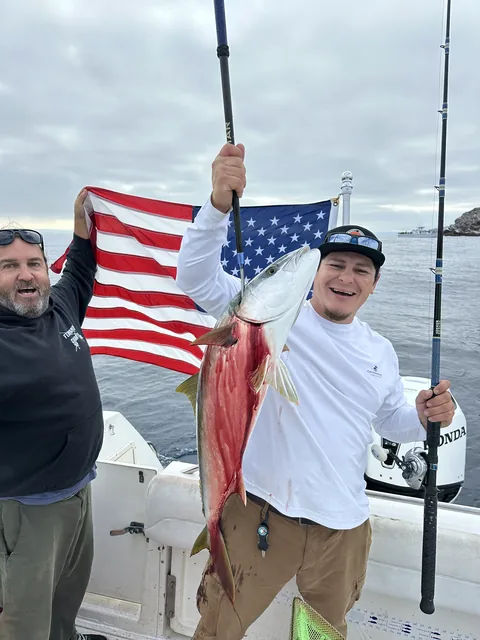 Anglers celebrating a yellowtail under the American flag.