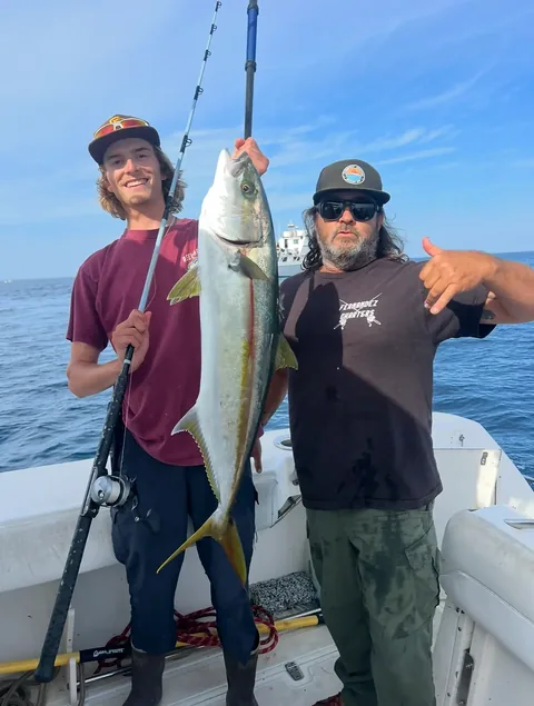 A young angler and Captain Pablo showing off a bright yellowtail offshore.